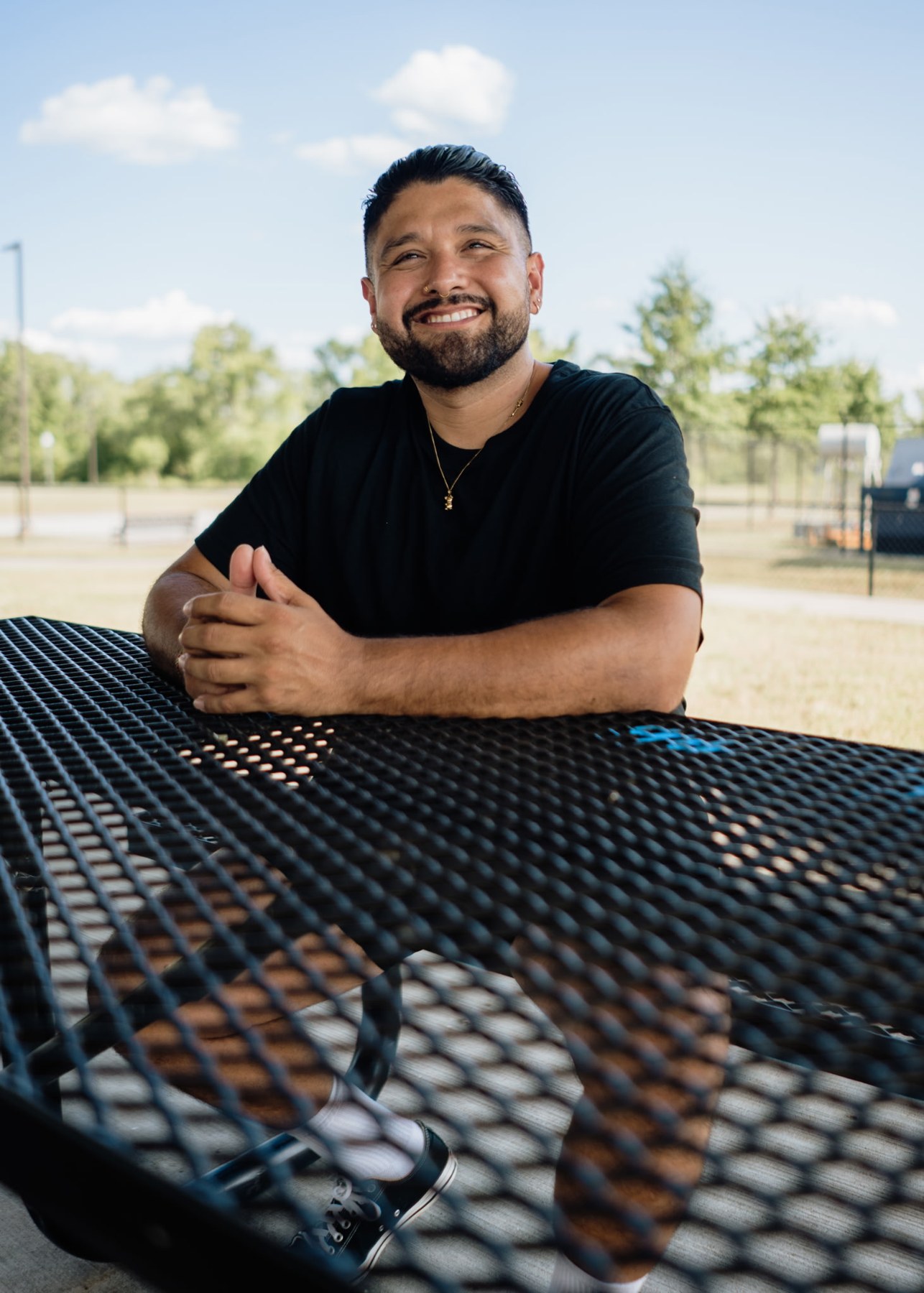 Armando seated at a picnic table on a sunny day in the park